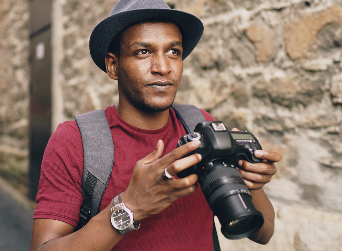 Dark.skinned man with camera observing his surroundings