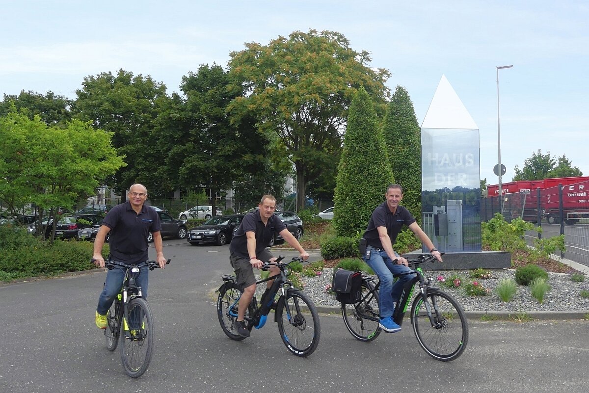 Drei Männer fahren mit Fahrrädern durch einen Park